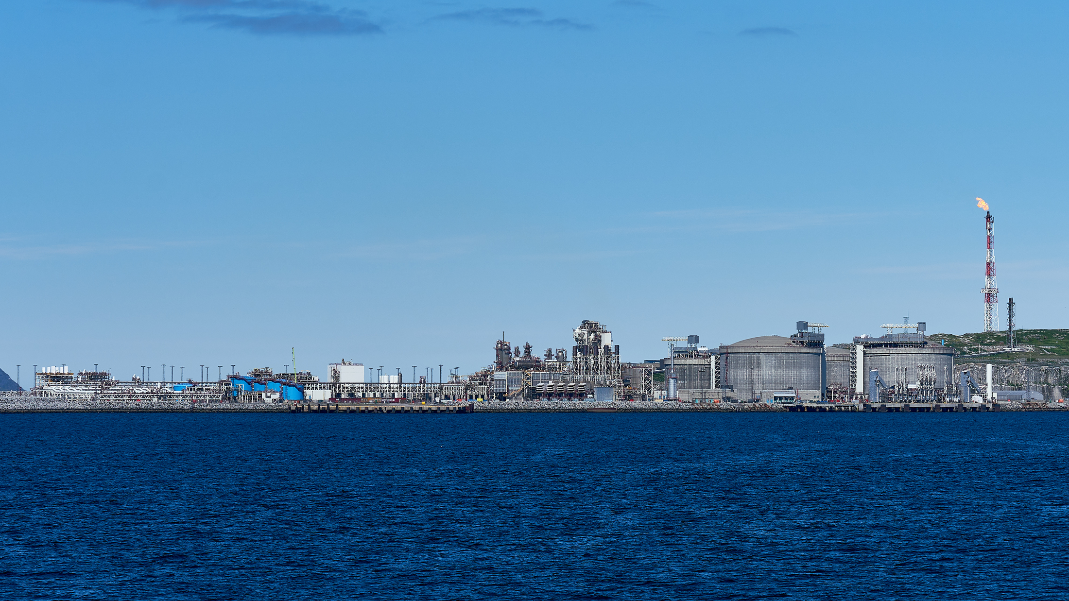 Aerial photograph of the Equinor Snohvit LNG export terminal on Melkoya island near Hammerfest, Norway, with the liquefaction train, full-containment storage tanks, control building, and pier visible from a north-westerly viewing angle.